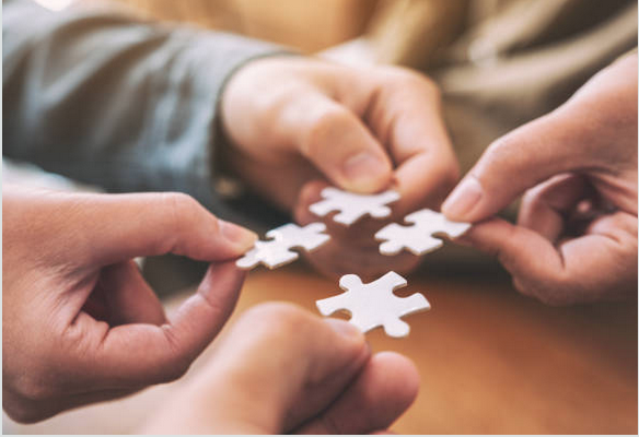 Photos des mains de deux personnes qui tiennent des pièces de puzzle suggérant la collaboration